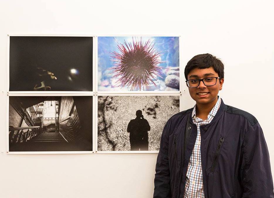 sujayphoto Sujay standing in front of a wall of photos