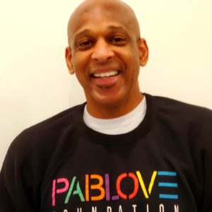 bald black man with a big friendly smile wearing a pablove foundation sweatshirt