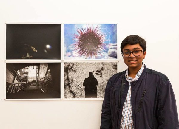 Sujay standing in front of a wall of photos
